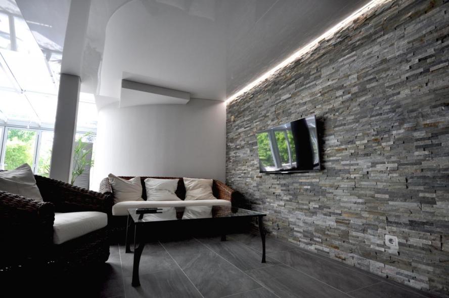 Spanndecke mit Beleuchtung in Wohnzimmer mit Steinwand 